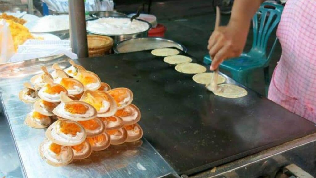 image of lady making Khanom Buang, which are small crepes, crispy from the outside filled with a sweet filling and is a very popular snack with Thai street foods vendors