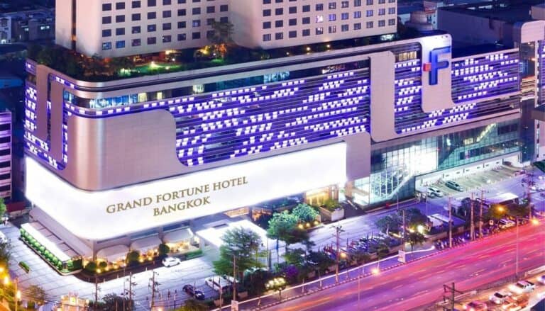 night view of the Grand Fortune hotel with lots of neon lights. The colors are purple and the hotel is white